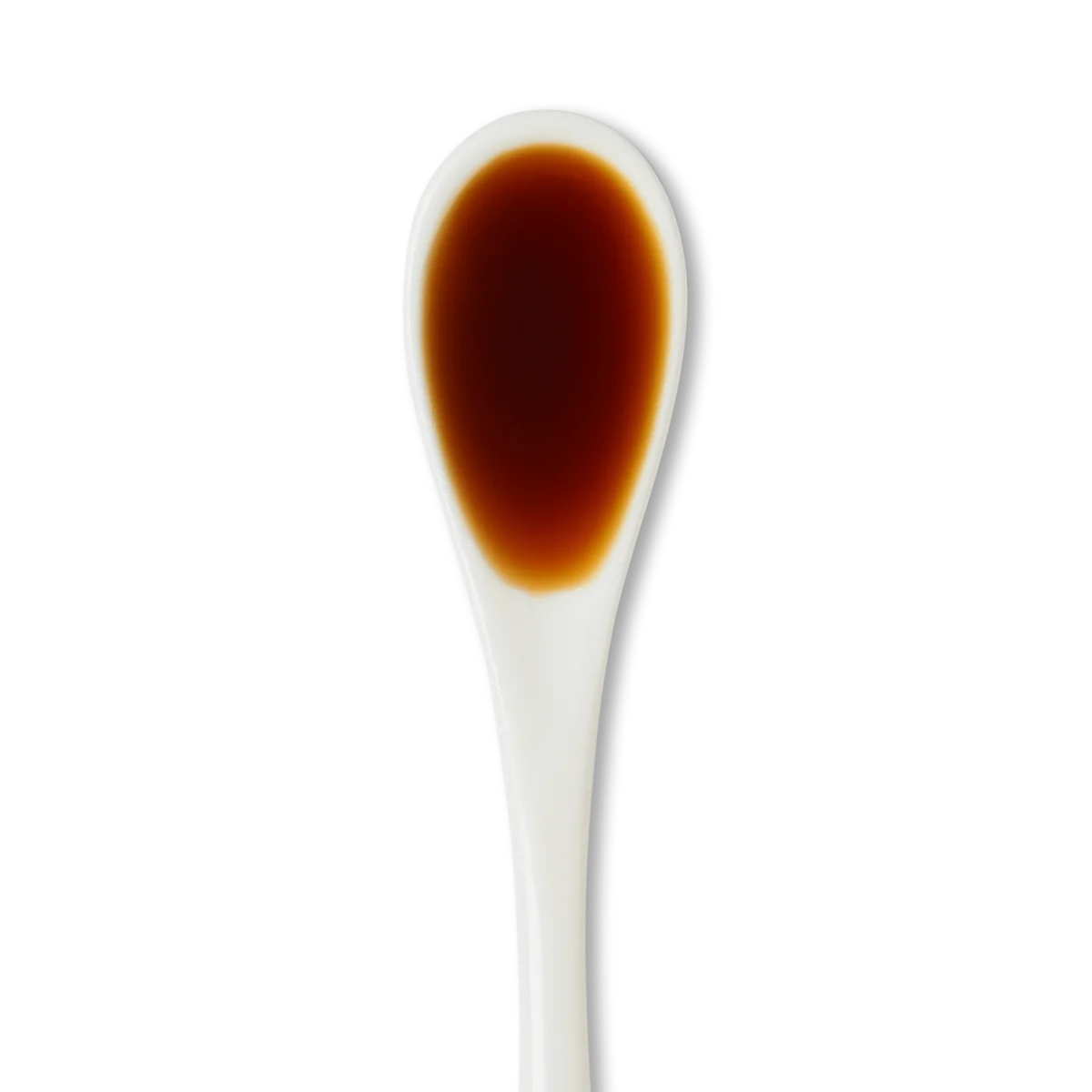 A white ceramic spoon filled with dark brown liquid, possibly soy sauce, against a white background.
