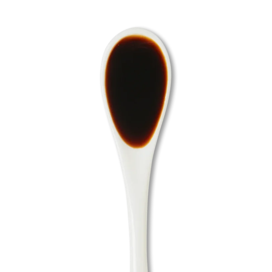 A white spoon filled with a dark brown liquid, likely soy sauce, against a white background.