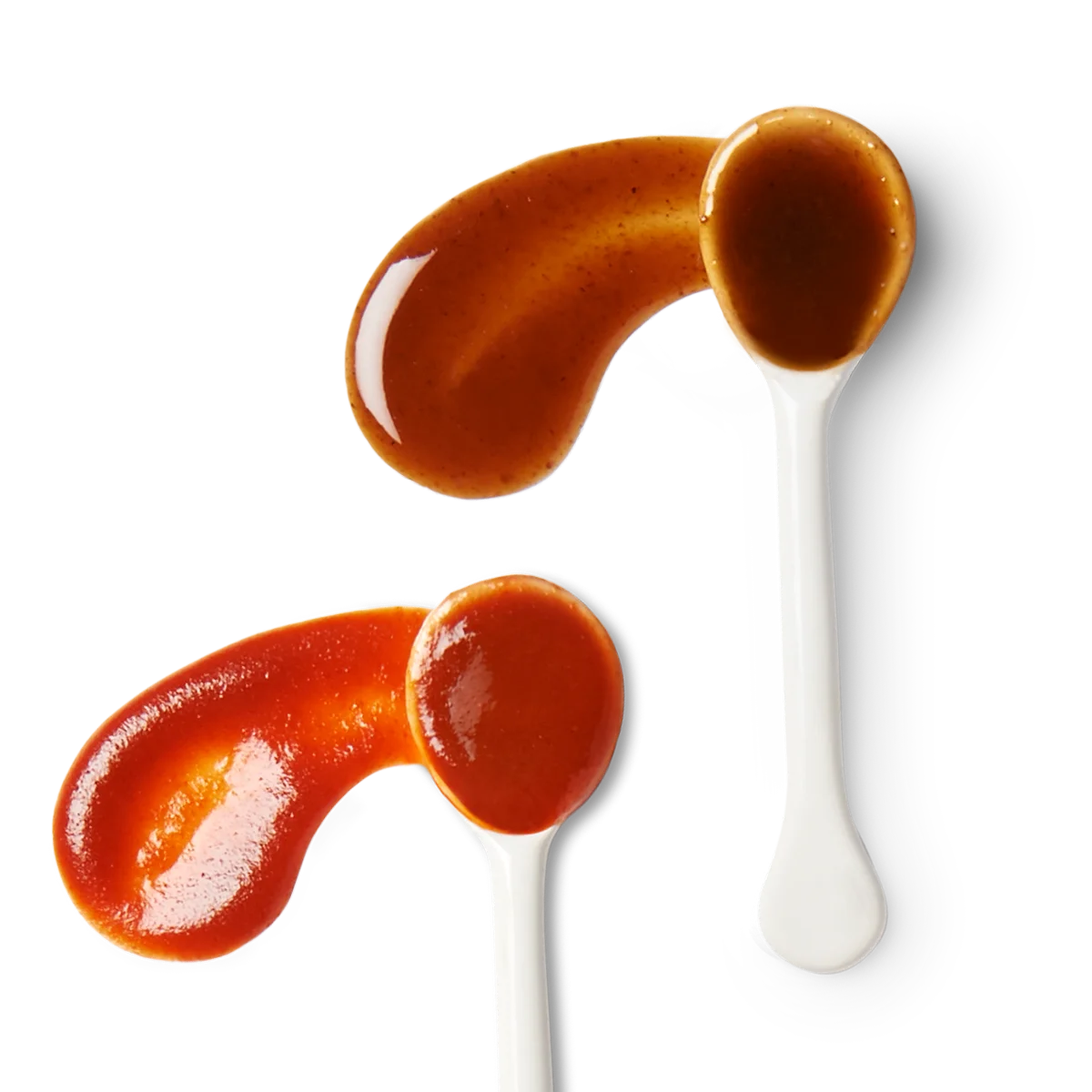 Two white spoons hold different sauces, one brown and one red, with each sauce partially spilled beside the spoon on a white background.