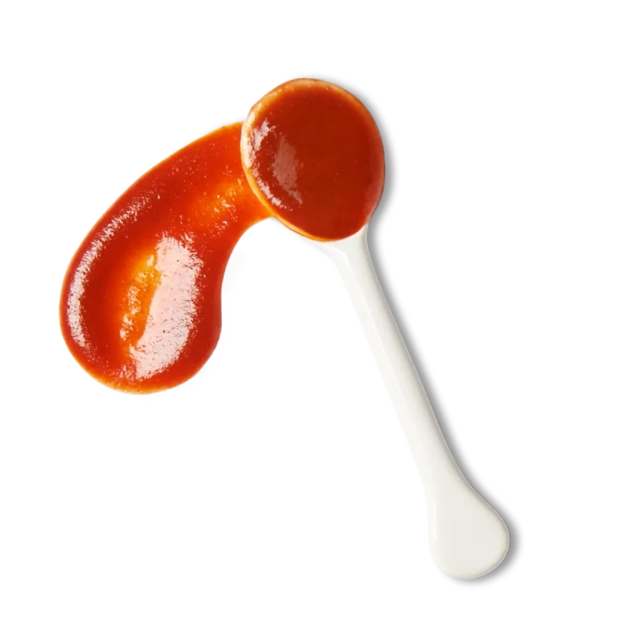A white spoon with tomato ketchup, some of which is spread in a curved shape next to it.