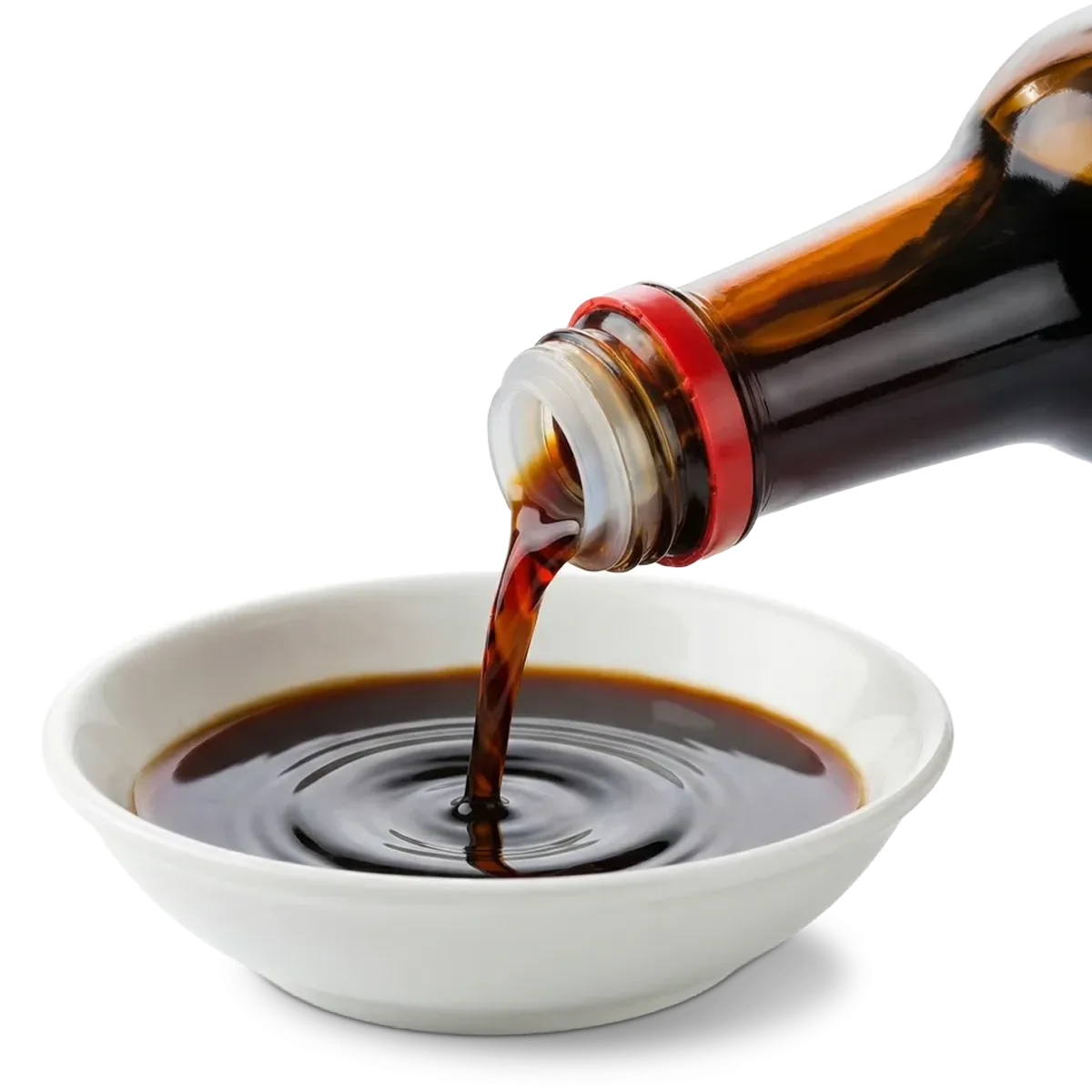 A bottle pours dark soy sauce into a small white bowl.