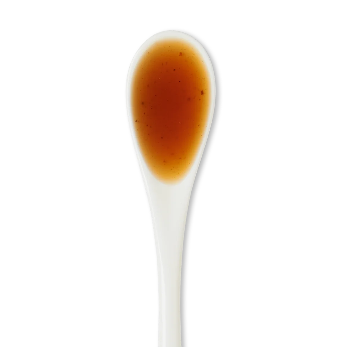 A white ceramic spoon filled with brown liquid against a white background.