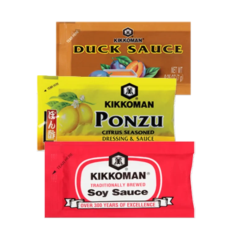 Three Kikkoman condiment packets: duck sauce (orange packet), ponzu citrus sauce (yellow packet), and traditionally brewed soy sauce (red packet).