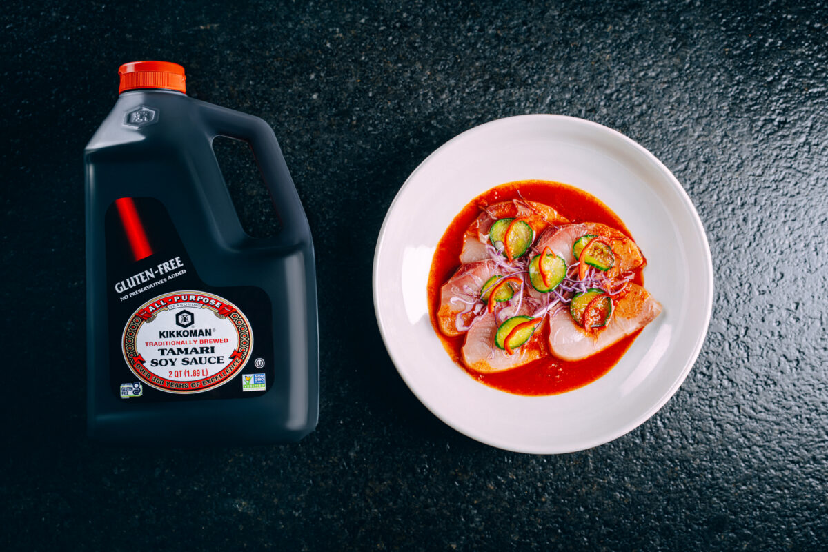 Plated Hamachi Crudo drizzled with gochujang-tomato sauce made with Kikkoman® Gluten-Free Tamari Soy Sauce, topped with thinly sliced red cabbage for color and crunch.