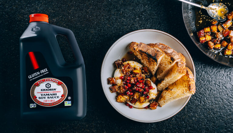 Sweet Potato Burrata plated with caramelized Korean sweet potatoes glazed in Kikkoman® Gluten-Free Tamari Soy Sauce, topped with pomegranate seeds and served alongside creamy burrata and toasted sourdough slices.