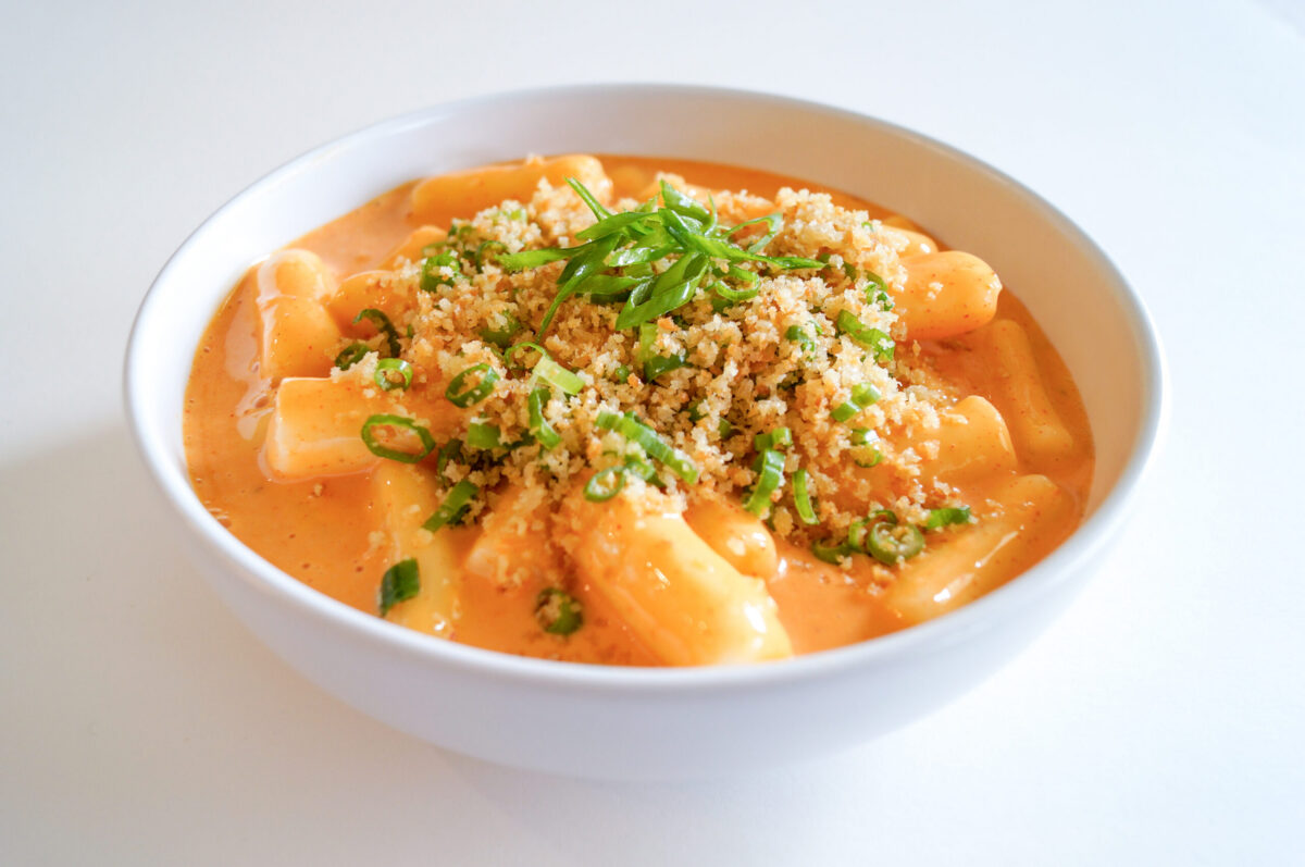 Plant-based Tteokbokki-style kimchi mac and cheese topped with crispy Kikkoman Panko and fried wonton crumbs, garnished with scallions.