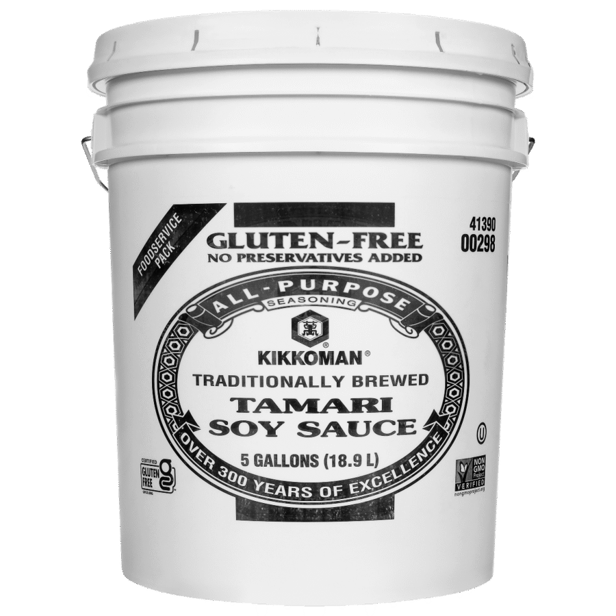 A white 5-gallon bucket of Kikkoman Tamari Soy Sauce with gluten-free and preservative-free labels on the front.