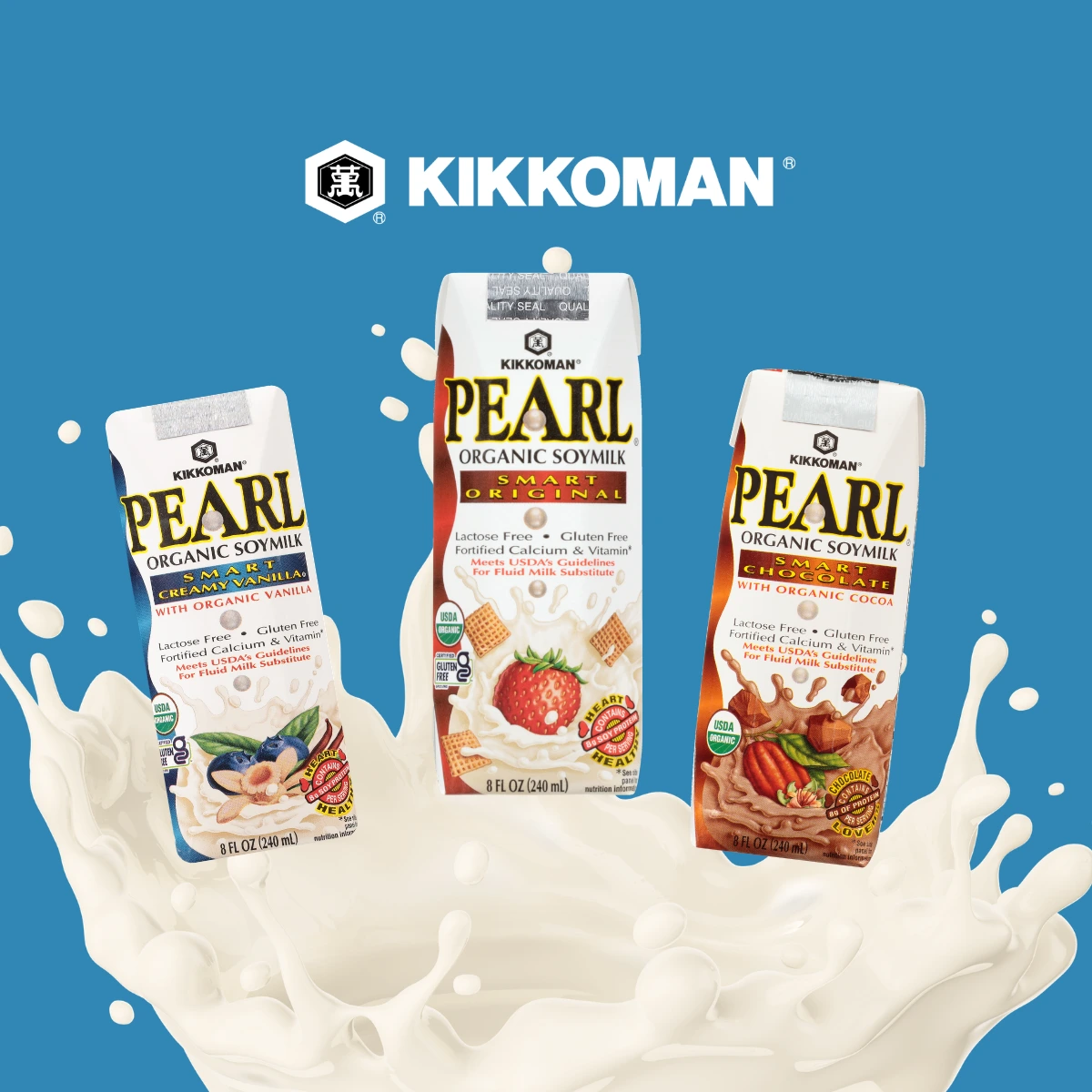 Three Kikkoman Pearl Organic Soymilk cartons—vanilla, original, and cocoa—stand above a splash of soymilk on a blue background with the Kikkoman logo above them.