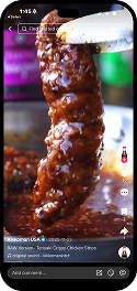 Close-up of a breaded chicken tender being dipped into barbecue sauce, with a blurred background and TikTok interface visible on a smartphone screen.