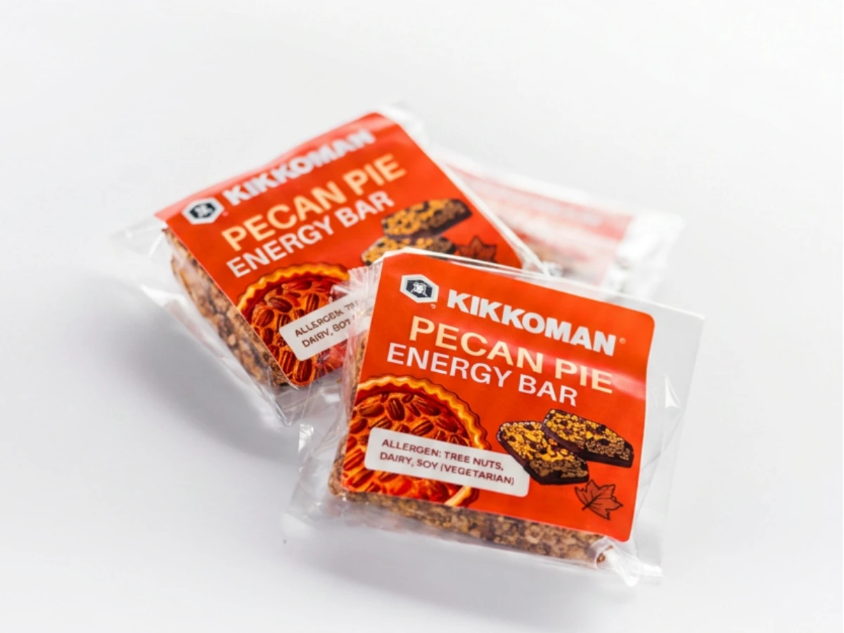 Two individually wrapped Kikkoman pecan pie energy bars with orange labels, featuring images of the bar and a slice of pecan pie.