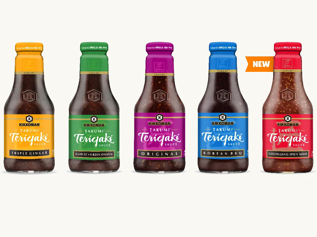 Five bottles of Kikkoman Takumi Teriyaki Sauce in different flavors: Triple Ginger, Garlic & Green Onion, Original, Korean BBQ, and Gochujang Spicy Miso.