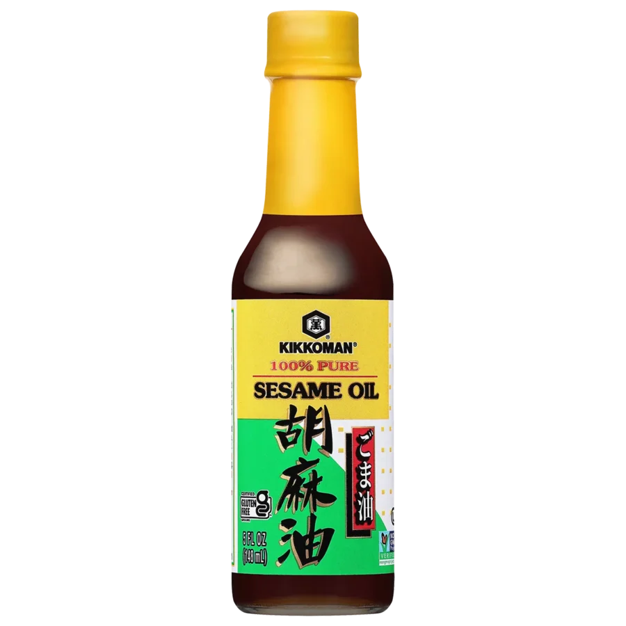 A bottle of Kikkoman 100% pure sesame oil with a yellow cap and a green and yellow label featuring English and Japanese text.