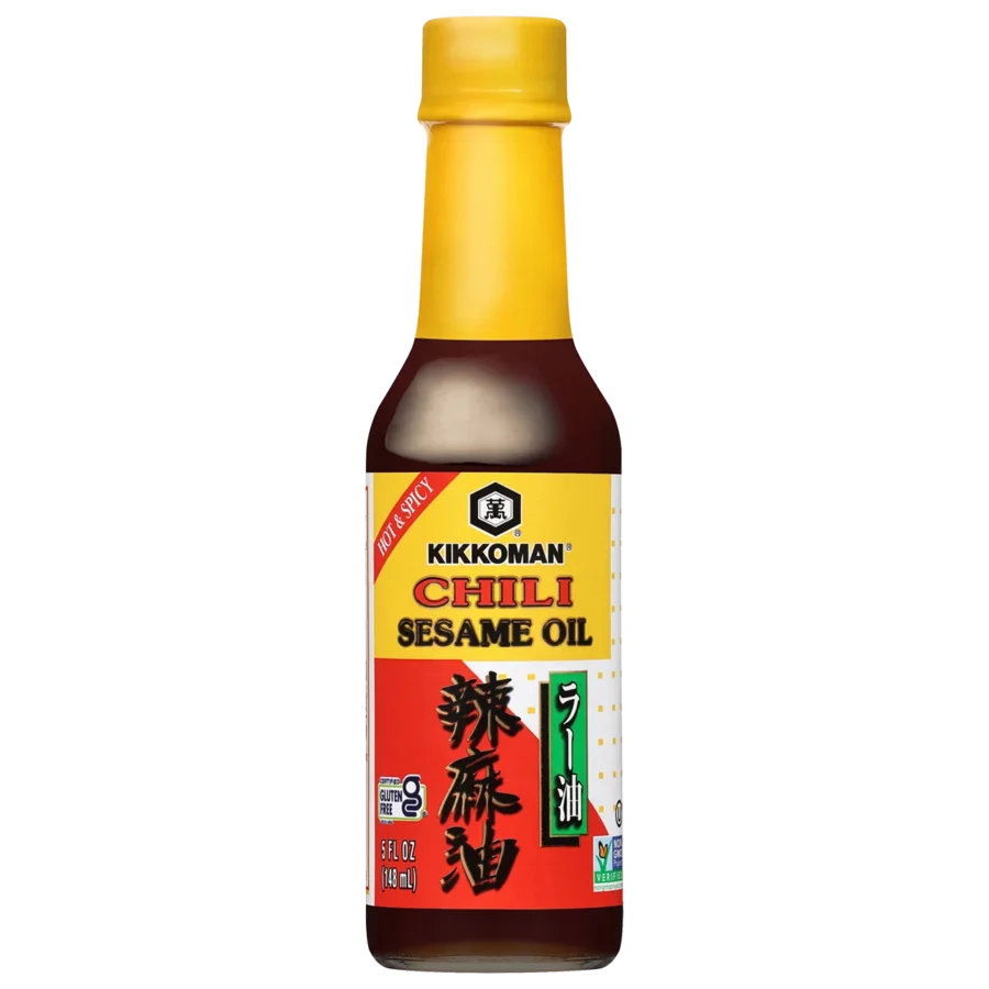 A bottle of Kikkoman Chili Sesame Oil with a yellow cap and red label displaying English and Chinese text.