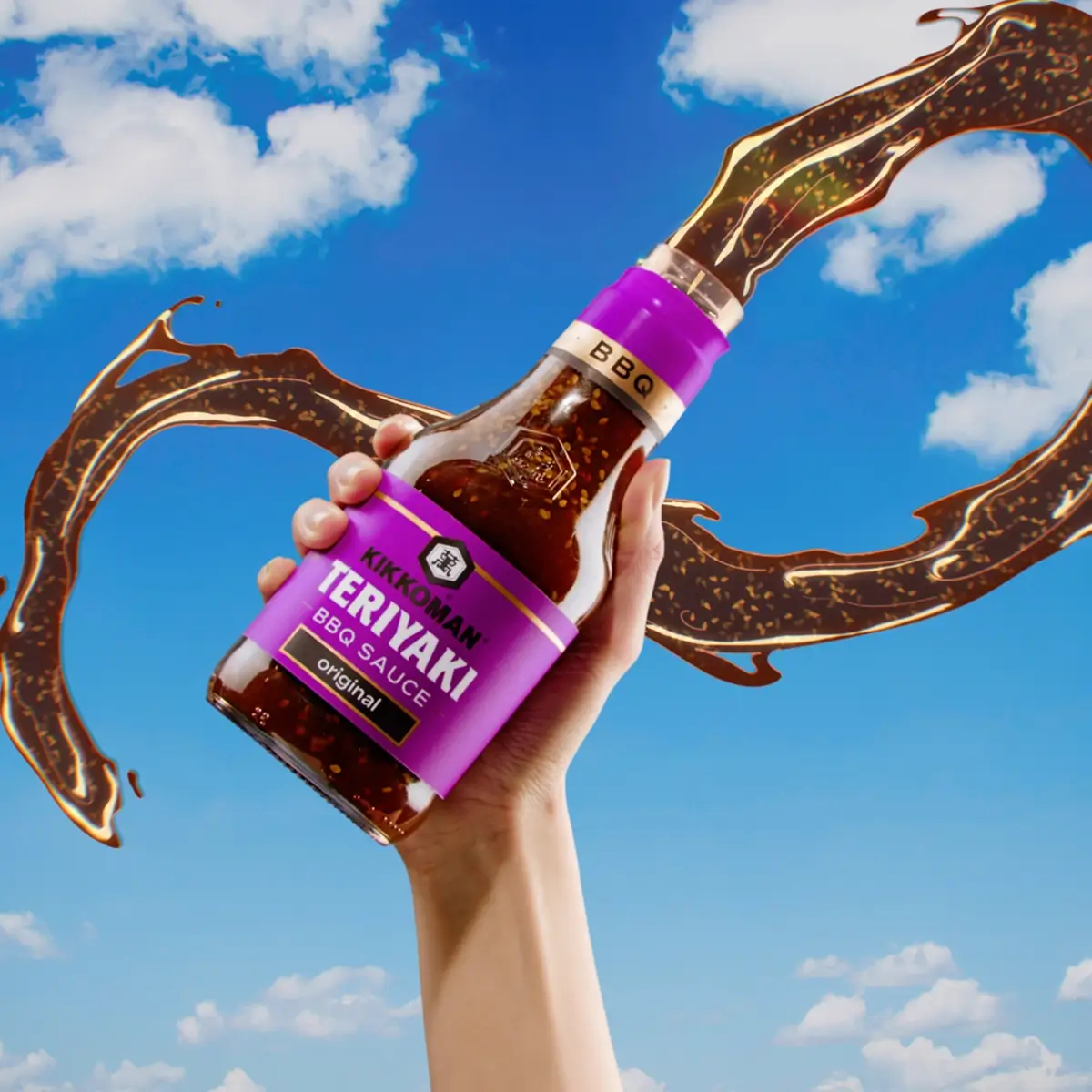 A hand holds a bottle of Kikkoman Teriyaki BBQ Sauce against a blue sky with clouds, with sauce splashing in the background.